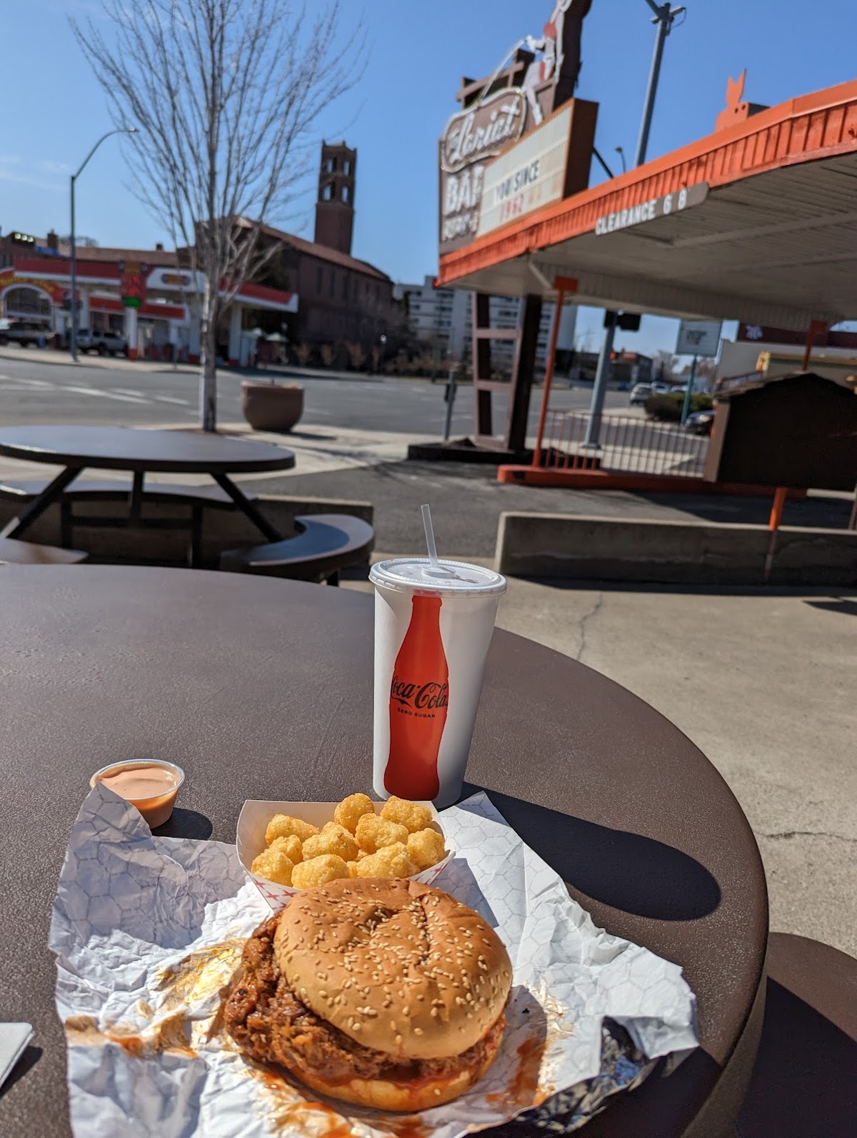 A pulled pork sandwich with tater tots and fry sauce on a picnic table at Lariat Bar-B-Q