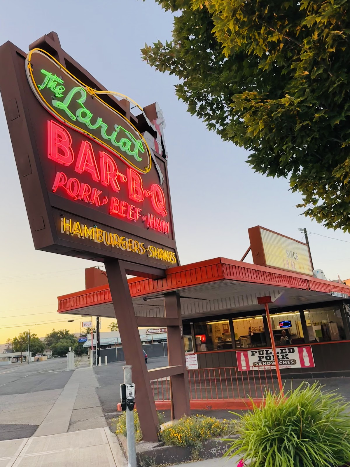 The Lariat Bar-B-Q neon sign glowing at golden hour over the drive-in on W Yakima Ave